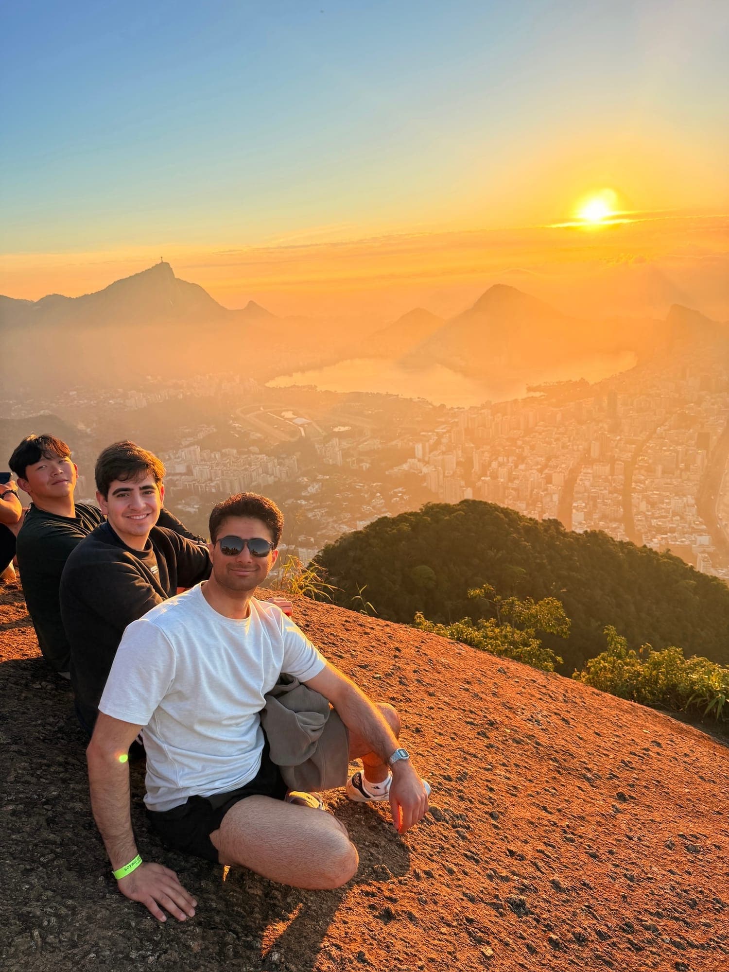 Friends sitting on a hilltop at sunset